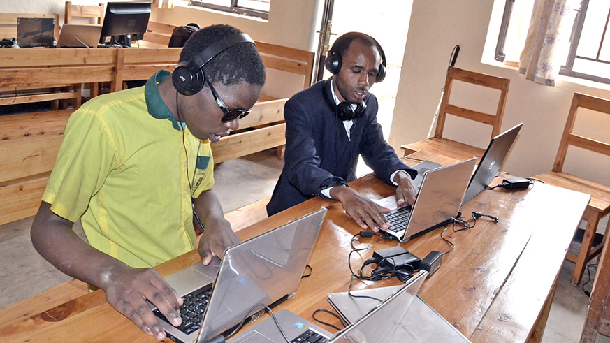 Innocent Vuguziga guides a visually impaired student during a computer lesson at Gatagara  Secondary School in Rwamagana. Photos by  Kelly Rwamapera