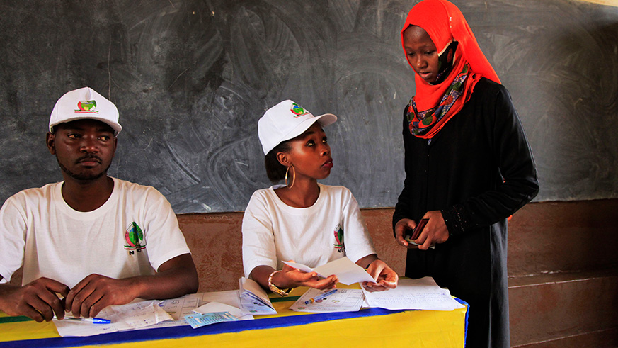 Polling agents help a voter to cast her vote during presidential elections at Groupe Scolaire Camp Kigali last year. Rwandans will vote for MPs on September 3. Sam Ngendahimana.