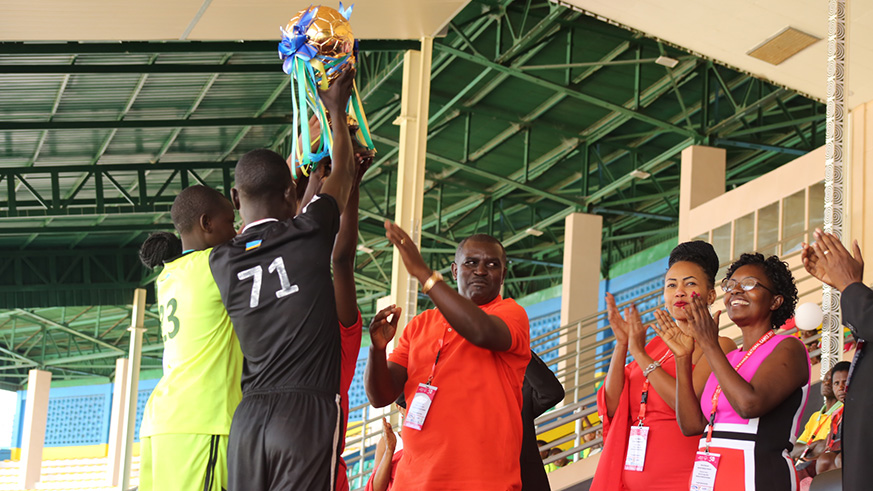 Emmanuel Bugingo (C) hands the trophy to captains during the closing ceremony of National Unified Games 2018 for athletes with intellectual disabilities yesterday at Amahoro stadium. Jejje Muhinde.