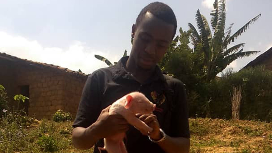 Dukundane carries a piglet. Joan Mbabazi.