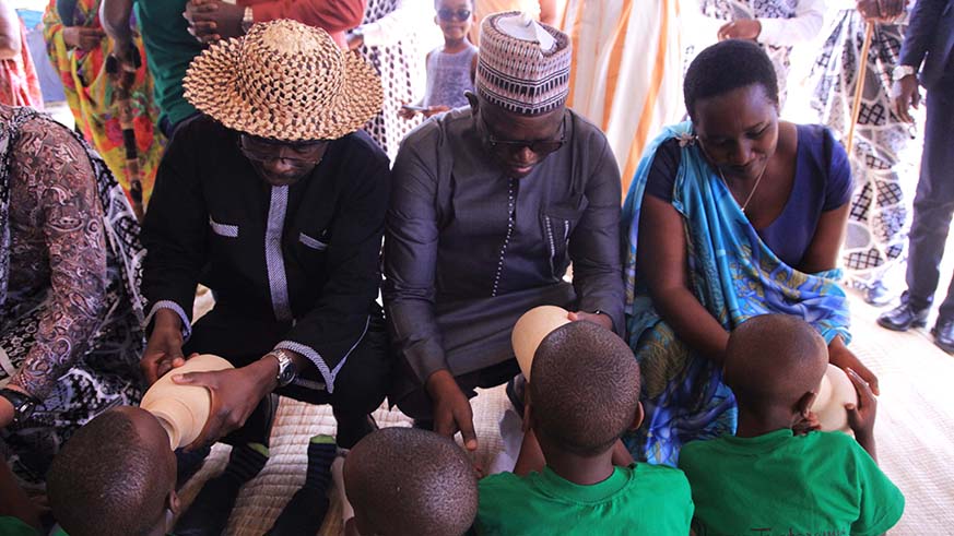L-R: Burkina Faso Minister for Culture, Arts and Tourism Abdoul Karim Sango; Senegalese Minister for Culture, Abdou Latif Coulibaly, and Rwandau2019s Minister for Sports and Culture, Julienne Uwacu, give milk to children during Umuganura celebrations in Nyanza District yesterday. Uwacu called on Rwandans to work together to contribute to the countryu2019s development programmes, encouraging citizens to preserve the culture of sharing their harvests. Sam Ngendahimana.