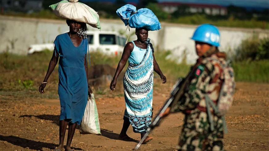 Displaced women carry goods as a Nepalese peacekeeper from the United Nations Mission in South Sudan (UNMISS) patrols outside the premises of the UN Protection of Civilians (PoC) site in Juba on Oct. 4, 2016. Net.