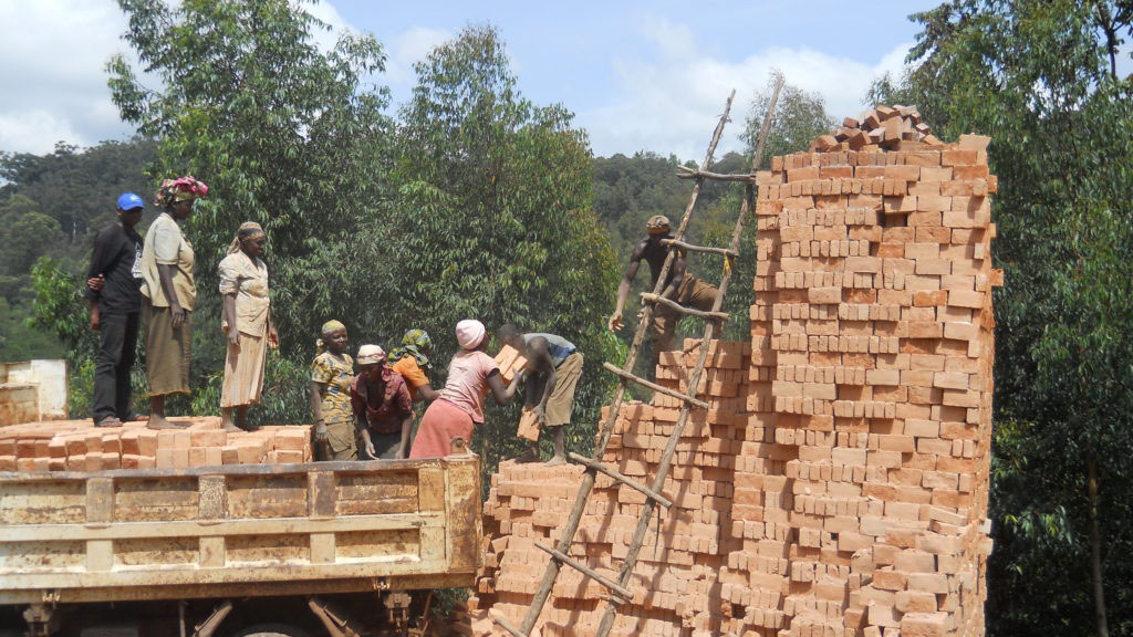 Beneficiaries load bricks for sale. 