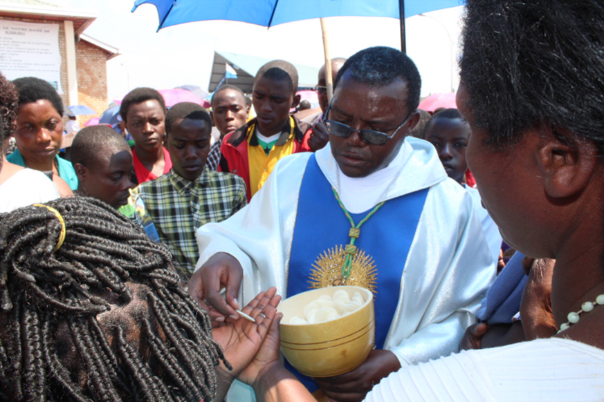 Christians receive holy communion from CÃ©lestin Hakizimana of Cyangugu Diocese at Kibeho yesterday. Thousands of Catholic pilgrims who turned up at Kibeho Holy Land to celebrate Assumption Day have been urged to keep faith and love. Jean dâ€™Amour Mbonyinshuti.