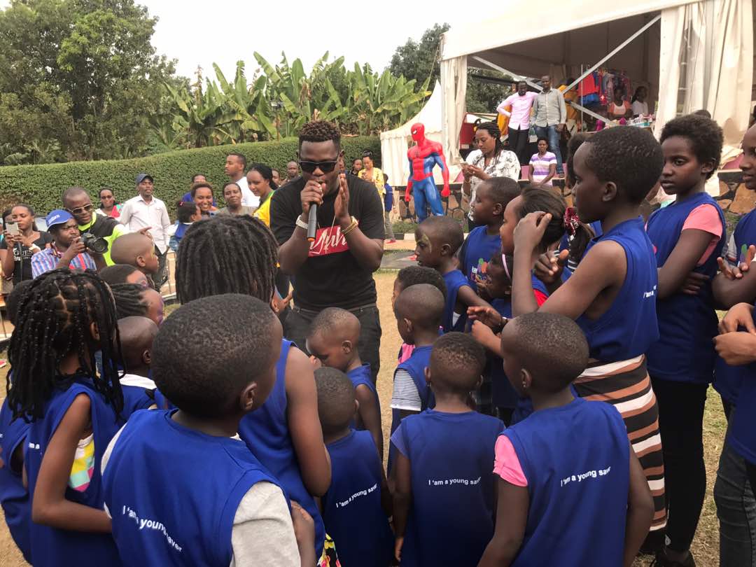 Bruce Melodie entertains children at a past event at Spiderman Game Centre in Masaka. Circled is Arthur Nkusi. Courtesy