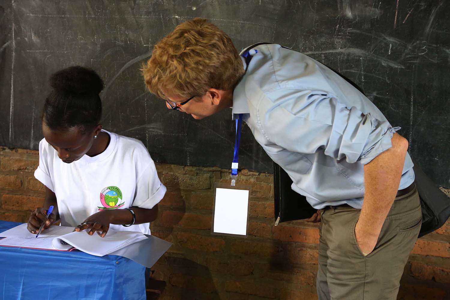 A Europian Union observer (R) checks the voters list with a NEC volunteer at Groupe Scolaire Kimironko II polling station. Sam Ngendahimana.