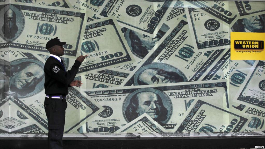 A security guard walks past a montage of old U.S. dollar bills outside a currency exchange bureau in Kenya's capital Nairobi, July 23, 2015. Net.