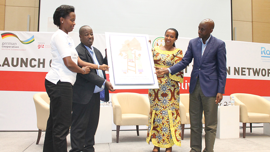 The ministers for Gender and Family Promotion and Local Government Espu00e9rance Nyirasafari (2nd R) and Francis Kaboneka (left) respectively, with newly elected head of Rwanda Network of Women in Local Government, Marie-Chantal Rwakazina (L), and the RALGA Chairperson Innocent Uwimana with the logo of the newly launched network yesterday. Courtesy. 