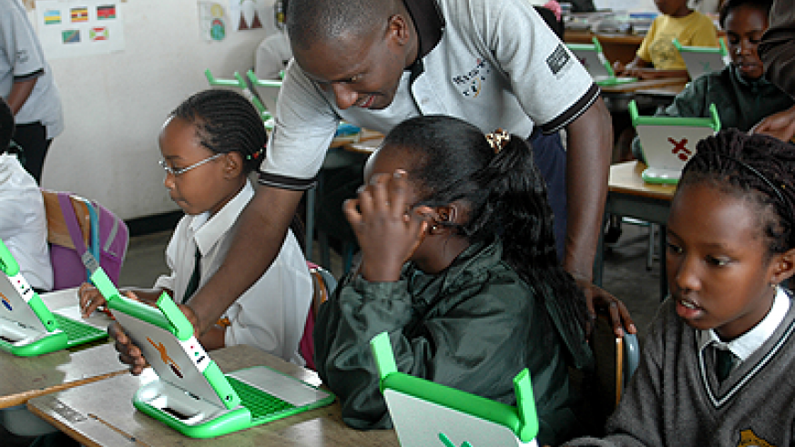 A teacher guides pupils on how to use OLPC computers.