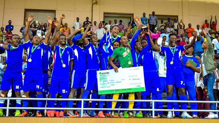Rayon Sports players, joined by some of their fans, celebrate with their trophy and dummy cheque after beating APR 1-0 to retain the title at Amahoro National Stadium on Sunday. Courtesy.