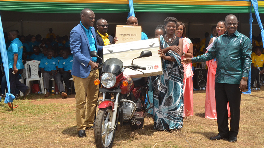 Aloysie Girabawe (2nd right), who emerged the best teacher nationwide in 2018, is awarded a motorbike, a flat screen TV and a laptop, as Education Minister Eugene Mutimura (right) and other officials congratulate her during the celebrations of the World Teachersu2019 Day in Rwamagana District yesterday. Jean de Dieu Nsabimana.
