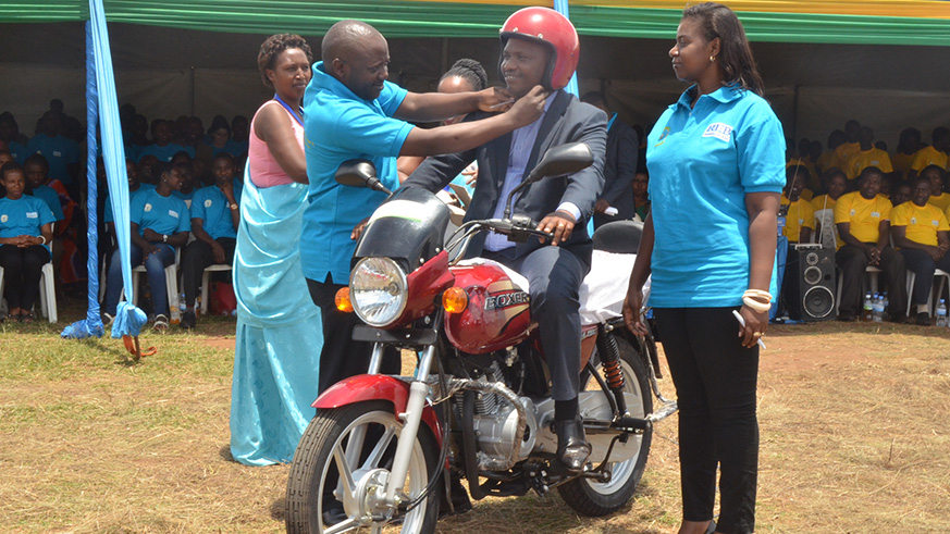 Eastern-Province-Executive-Secretary-Kizito-Habimana,-putting-a-helmet-on-James-Asiimwe-who-received-a-motorbike-from-Umwalimu-SACCO-as-the-best-customer