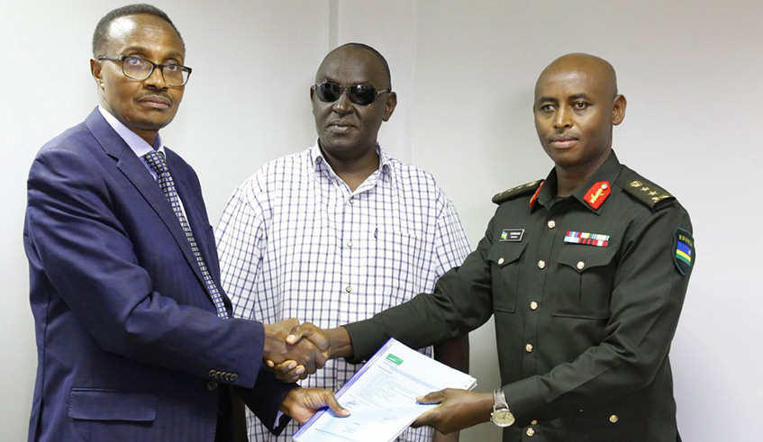 Defence Minister Albert Murasira (left) hands over to Maj Gen Emmanuel Bayingana as Chief Executive Officer of Zigama Credit and Savings Society. Centre is James Ndahiro, the armed forcesu2019 banku2019s board chairman, Bayingana replaces Murasira, who has been at the helm of the financial institution since 2012. Courtesy.