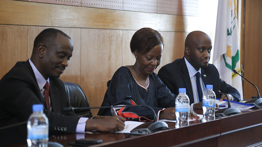 Richard Sezibera and Louise Mushikiwabo sign documents during the handover ceremony.