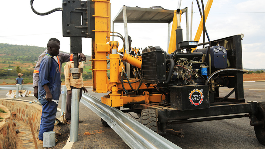 Road construction workers install road rails. Sam Ngendahimana.