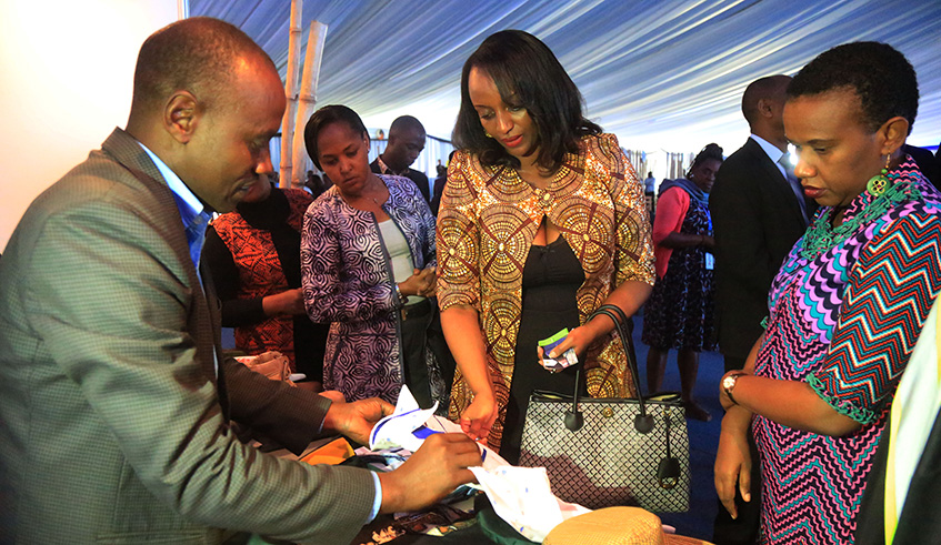 Minister of Trade and Industry Soraya Hakuzumuremyi (centre) chats with an exhibitor, as she tours a mini expo during the launch of Made- in-Rwanda logo, last week. /Sam Ngendahimana.