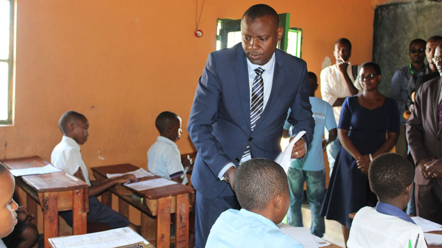 Minister Isaac Munyakazi distributes exam paper at GS Kacyiru I during the launch of exams. / Courtesy