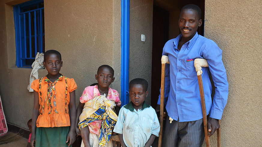 Antoine Mukeshimana poses with his children in front of his house in Rweru model village. Sam Ngendahimana.