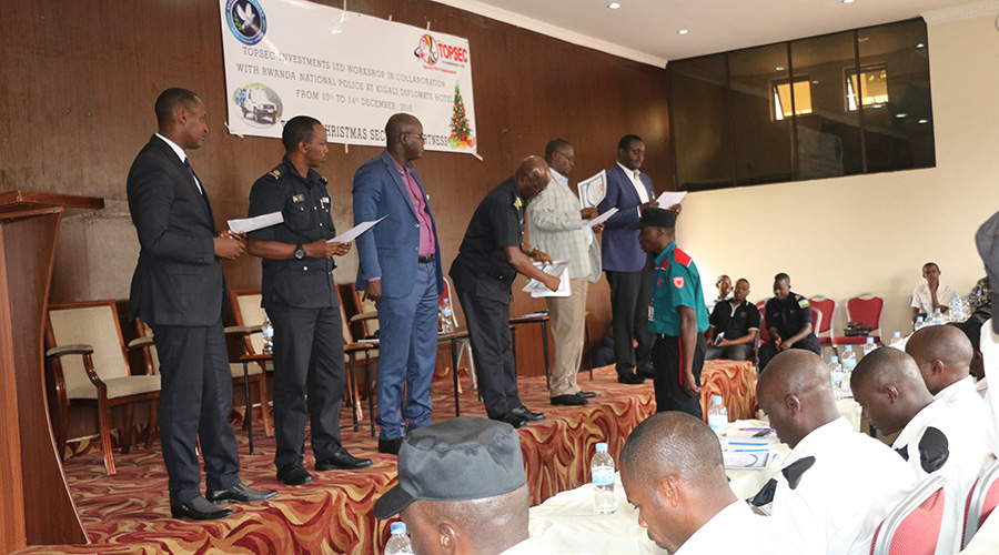 ACP Jean-Nepomuscene (bending forward) awards a certificate to a security guard while Andrew Nkurunziza the chairman at Private Security Forum (first left) looks on in Kigali yesterday. / Kelly Rwamapera