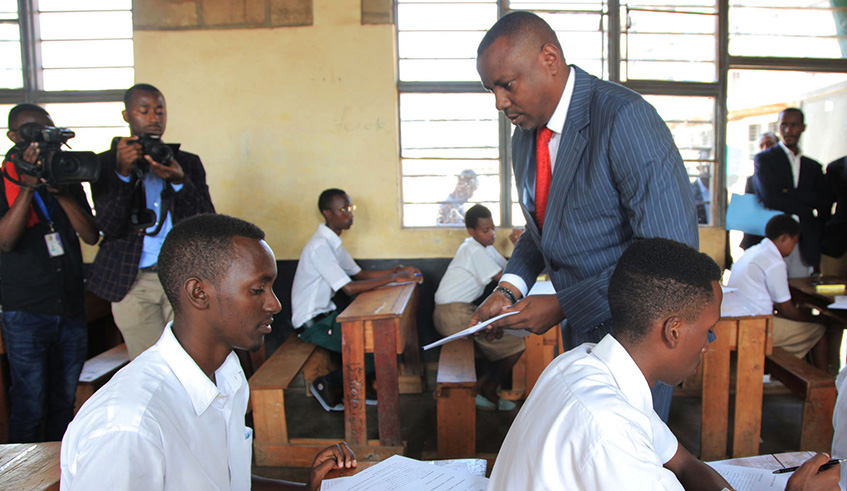 The State Minister for Primary and Secondary Education, Isaac Munyakazi distributes the exam questionnaires to students during a national exam. Sam Ngendahimana.