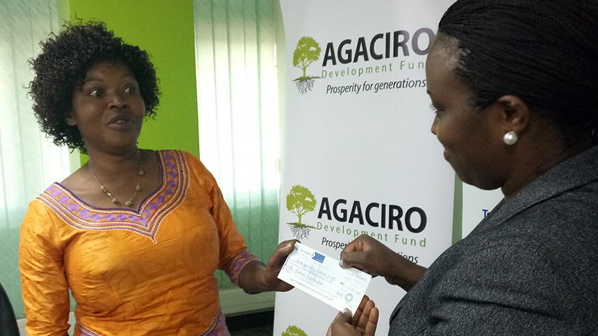 Sylivie Muneza, the President of the network of People Living with HIV handing over a cheque to Francine Uwamaliya, Head of Operations as a contribution towards  Agaciro Development Fund receive. Jean du2019Amour Mbonyinshuti