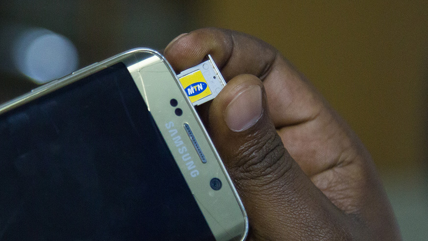A person inserts a sim-card in his mobile phone. Nadege Imbabazi.