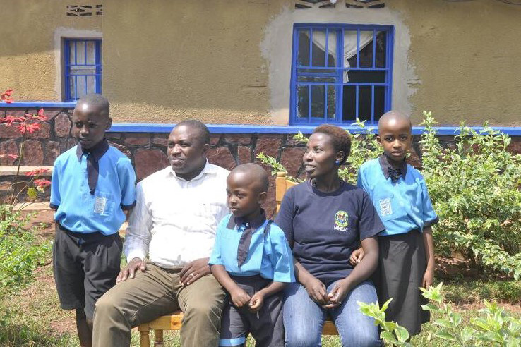 Sekamana with his family in front of their house.