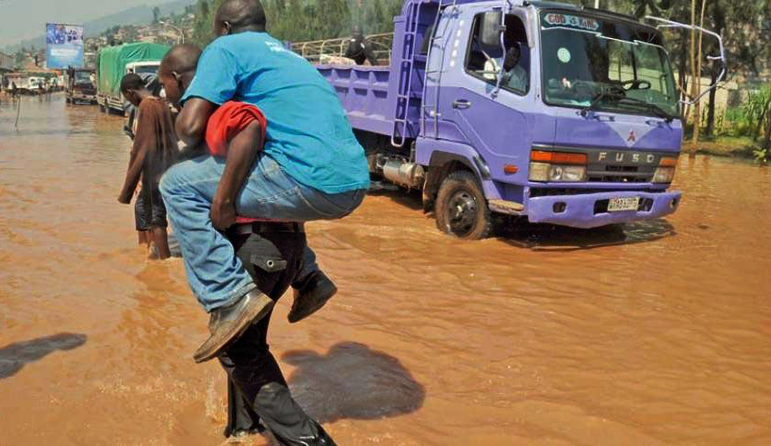 A man is carried across a flooded Nyabugogo highway in April 2012. The Ministry of Environment has outlined a plan to end flooding in the area. File.