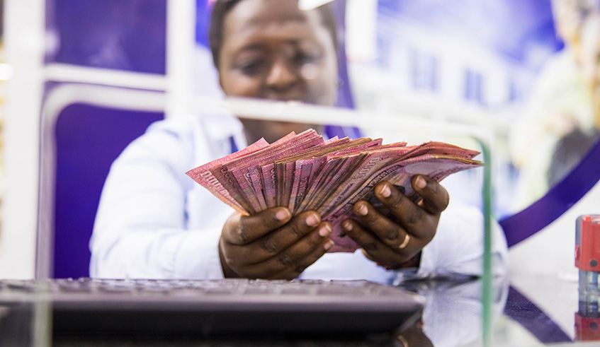 A teller counts money at a local bank.  Faustin Niyigena.