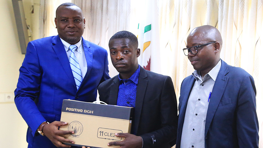 Pierre Byumvuhore, from EAV Kabutare receives a laptop as a reward for his performance from State Minister Isaac Munyakazi (Primary and Secondary Education) as his father looks on at the Ministry of Education headquarters in Kigali yesterday.  Photos by Sam Ngendahimana.
