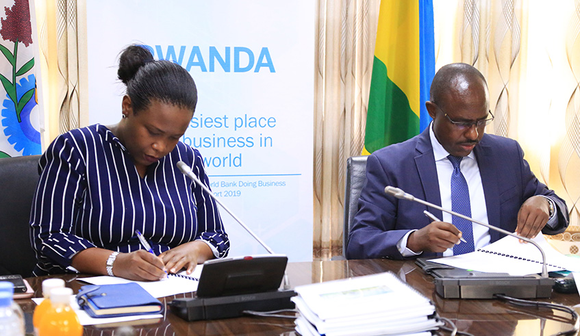 Rwanda Development Board chief executive Clare Akamanzi and Minister for Education Eugene Mutimura sign the agreement to hand over Carnegie Mellon University project in Kigali yesterday. Sam Ngendahimana.