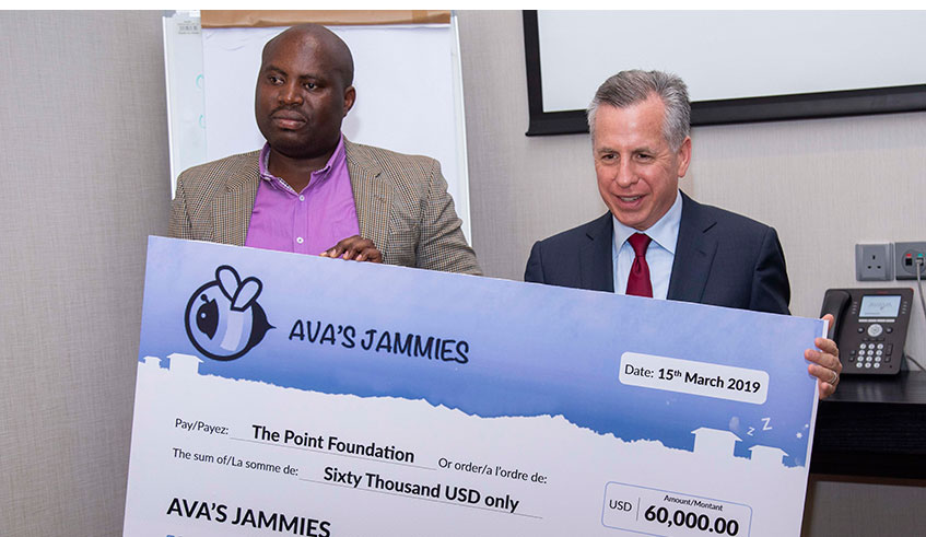 Avau2019s father, Marc Holtzman (R) presents a US $ 60,000 dummy cheque to Viateur Uwambajimana.