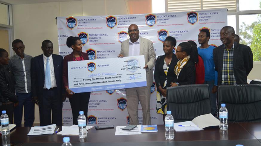The chairman and founder Prof. Simon Gicharu hands over the cheque to Imbuto foundationu2019s director-general Sandrine Umutoni