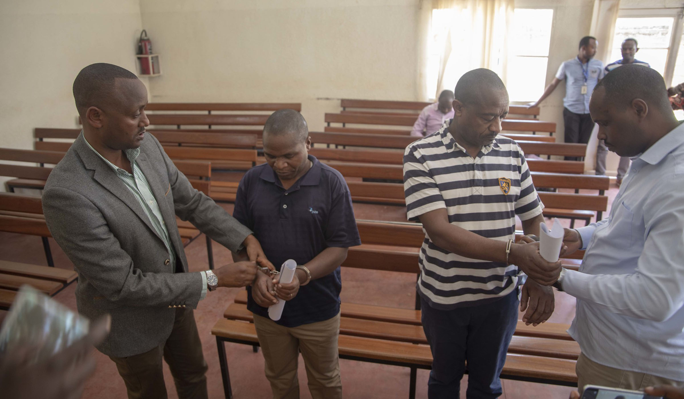 Lt Col Nsekanabo (2nd left) and Nkaka (2nd right) have their handcuffs removed before a judge at Gasabo Primary Court in Kigali on Monday. Emmanuel Kwizera.