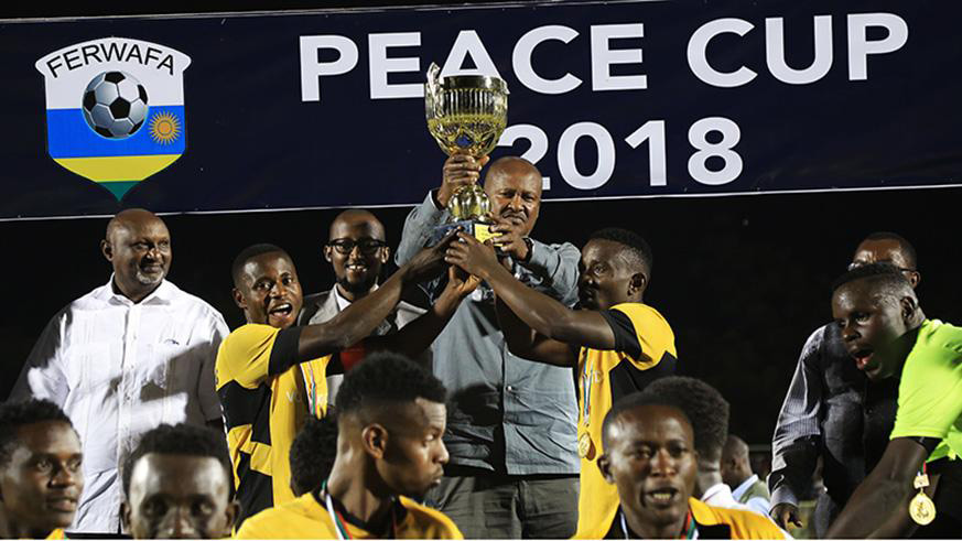 Ferwafa president Jean-Damascene Sekamana hands the Peace Cup trophy to Mukura Victory Sports players after they stunned Rayon Sports 3-1 on penalties at Kigali Stadium last August. File.
