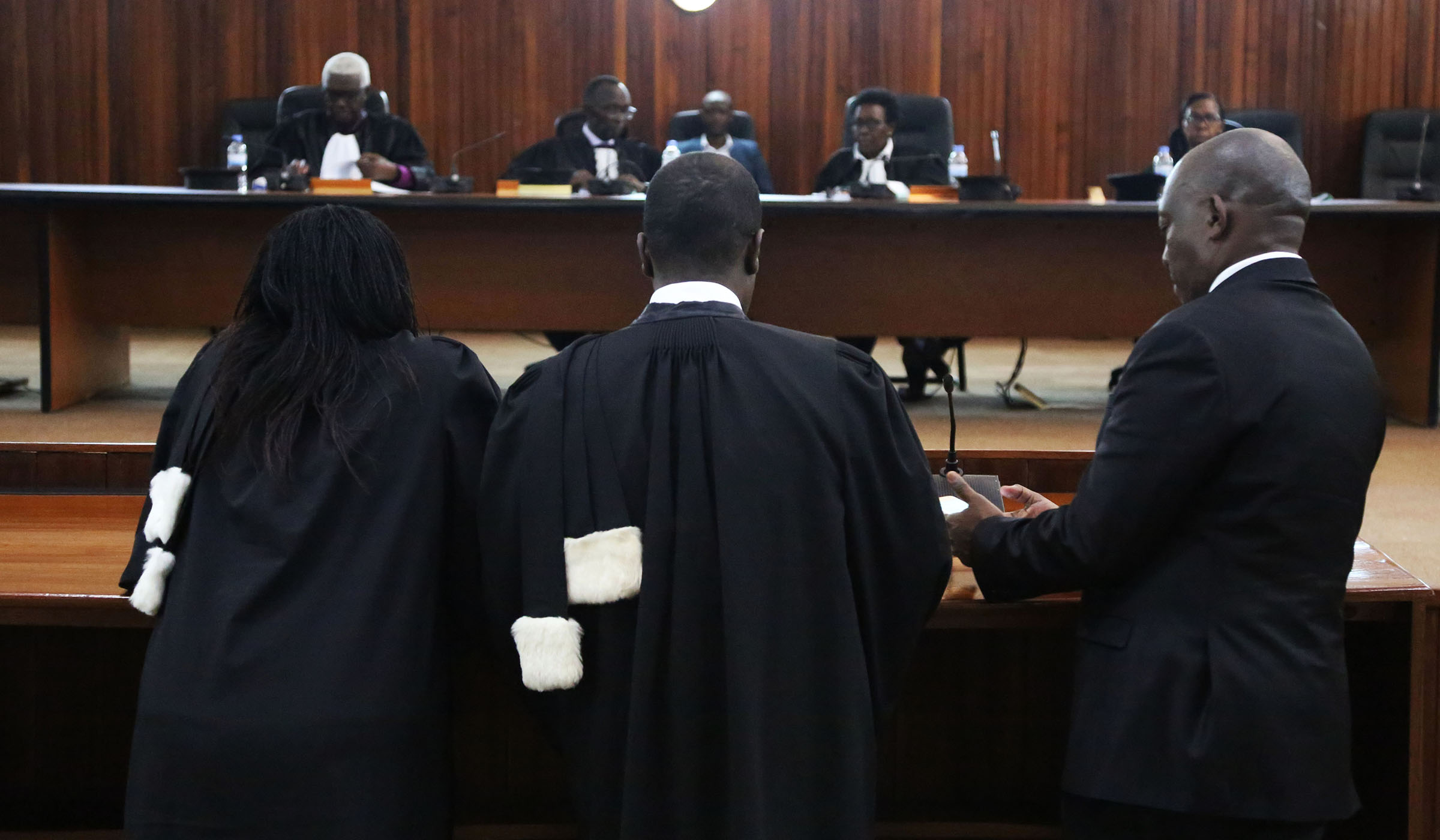 Richard Mugisha (right) with his lawyers Moise Nkundabarashi and Florida Kabasinga (left) sign a copy of the ruling at the Supreme Court in front of the justices on Wednesday. Sam Ngendahimana.