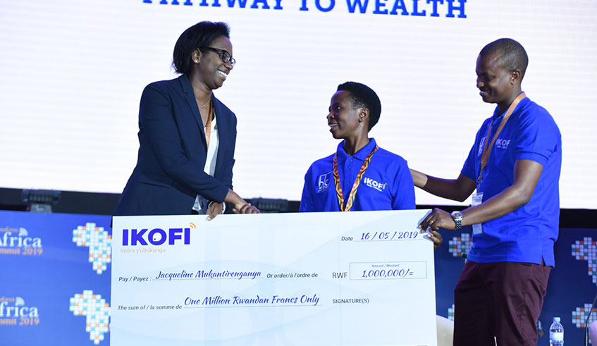 The first farmer to win 1 Million RWF in the u201cOne million per week Campaignu201d, Jacqueline Mukantirenganye receives a dummy from BK CEO Diane Karusisi. (Courtesy)
