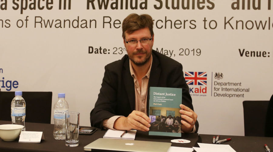 Dr Phil Clark poses with the book he authored about the ICCu2019s failure to deliver justice. / Craish Bahizi