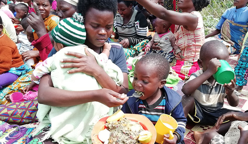A mother feeds her child with food prepared at a village kitchen in Nyamagabe District on June 7, 2019. Hudson Kutesa.
