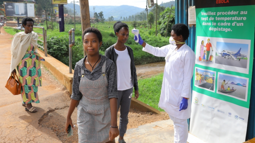 A health worker uses a thermometer to test temperature checking for signs of Ebola virus to passengers from Uganda to Rwanda at Gatuna Border in Gicumbi District on May 27, 2019