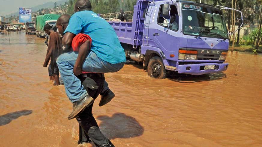 A man is carried through a flooded area in Nyabugogo. The government is set to bring in mobile bridges to deal with problem. / File