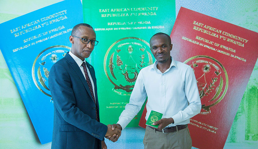Franu00e7ois-Ru00e9gis Gatarayiha, the Director General of Emigration and Immigration, shakes hands with Enock Niyonzima from Rusizi District, after the latter received a service passport during the launch of the Rwanda East Africa electronic passport in Kigali yesterday. Emmanuel Kwizera.