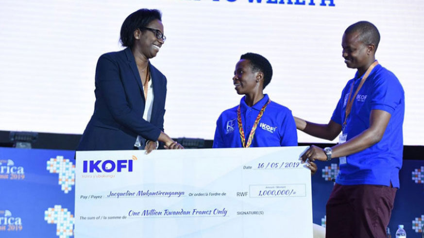 Bank of Kigali CEO Dr Diane Karusisi hands a dummy check to a lucky subscriber. Ikofi was launched in May this year to increase farmers eligibility to access credit. Net photo.