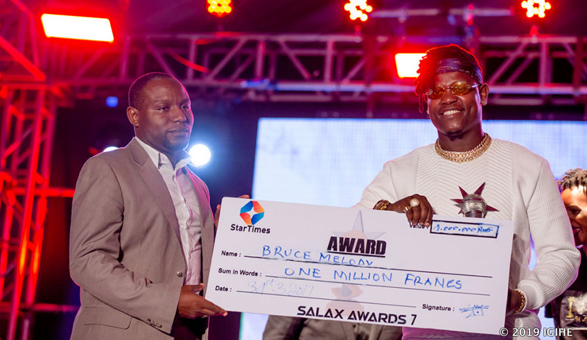 Ahmed Pacifique (L) gives one of the winners of Salax Awards Bruce Melody, a dummy cheque of over Rwf1 million at the event. Courtesy.