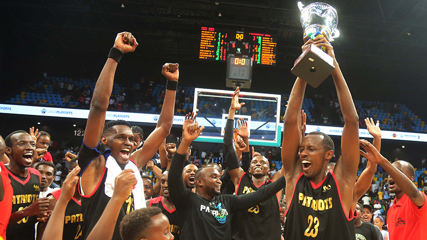 Steven Hagumintwari, who scored 8 points in Game 7, lifts the trophy aloft after Patriots edged REG 65-59 to retain the Bank of Kigali Basketball National League title at Kigali Arena on Saturday. / All photos by Sam Ngendahimana