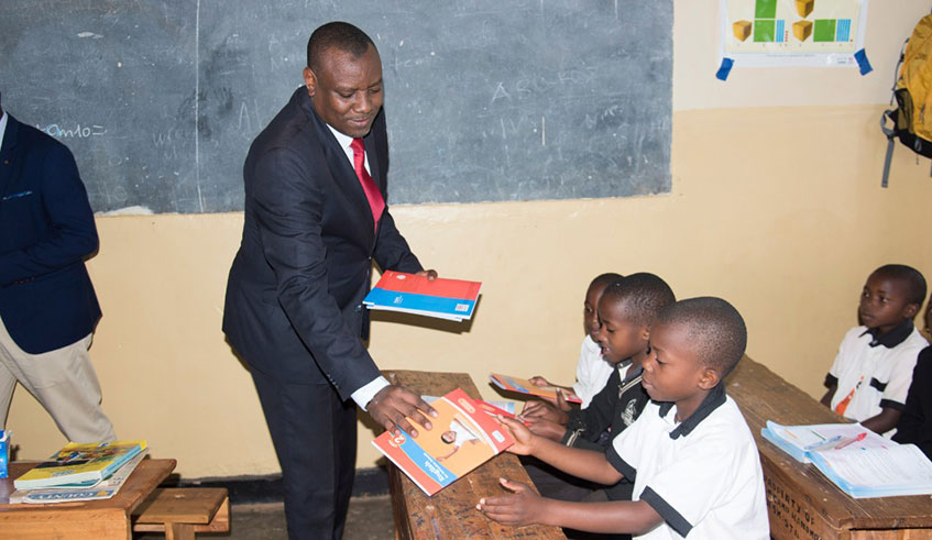 Isaac Munyakazi, the State Minister in charge of Primary and Secondary Education, distributes textbooks to pupils at Camp Kigali School on September 30. Courtesy.