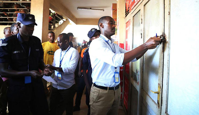 A Rwanda Revenue Authority staff, accompanied by police officers, closes a shop during a crackdown on tax defaulters in Kigali last year. Sam Ngendahimana.