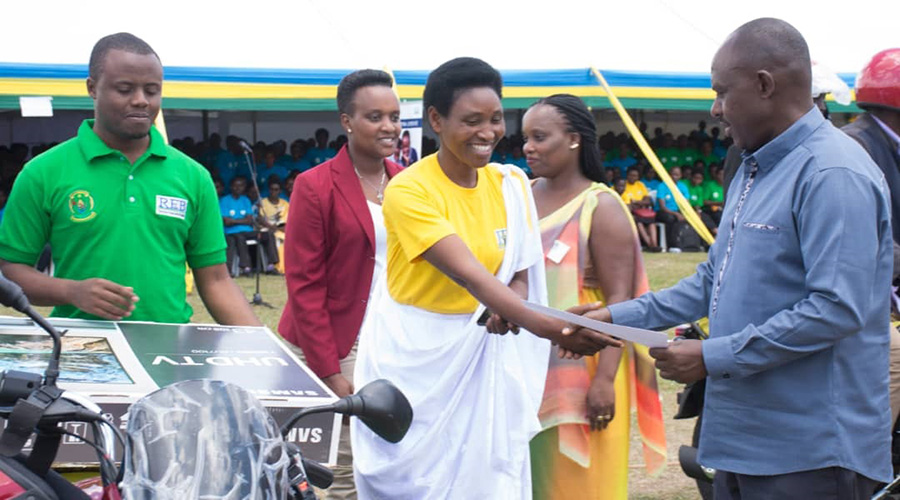 Beatha Ahishakiye (L) receives a motorcycle and a flat-screen TV from Minister of Education Eugu00e8ne Mutimura on World Teachers' day. / Jean de Dieu Nsabimana