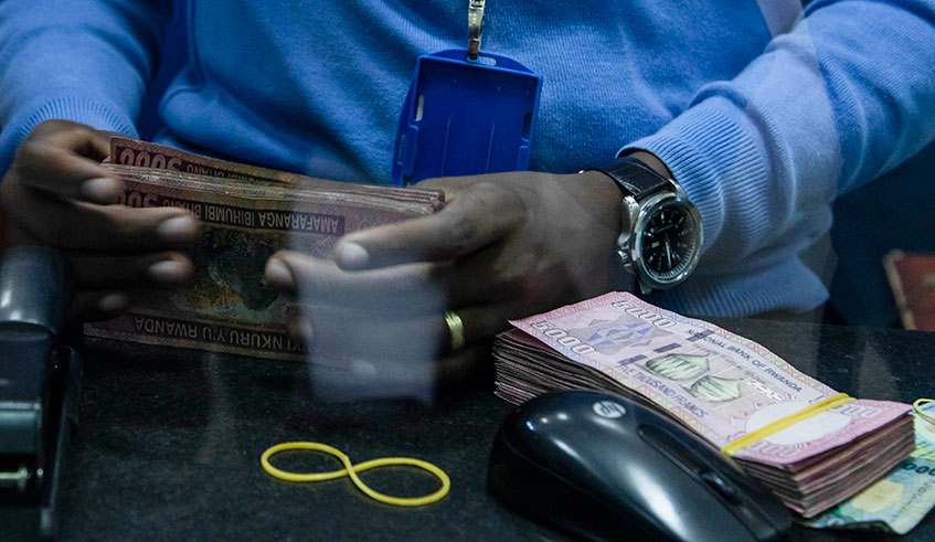A bank teller counts money at one of the commercial banks in Kigali. Emmanuel Kwizera.