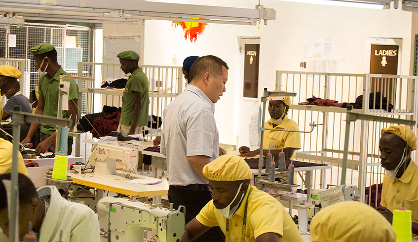 Chinese technician supervising factory workers inside the sewing department at Kigali based Chinese garments manufacturer in Special Economic Zone. Courtesy